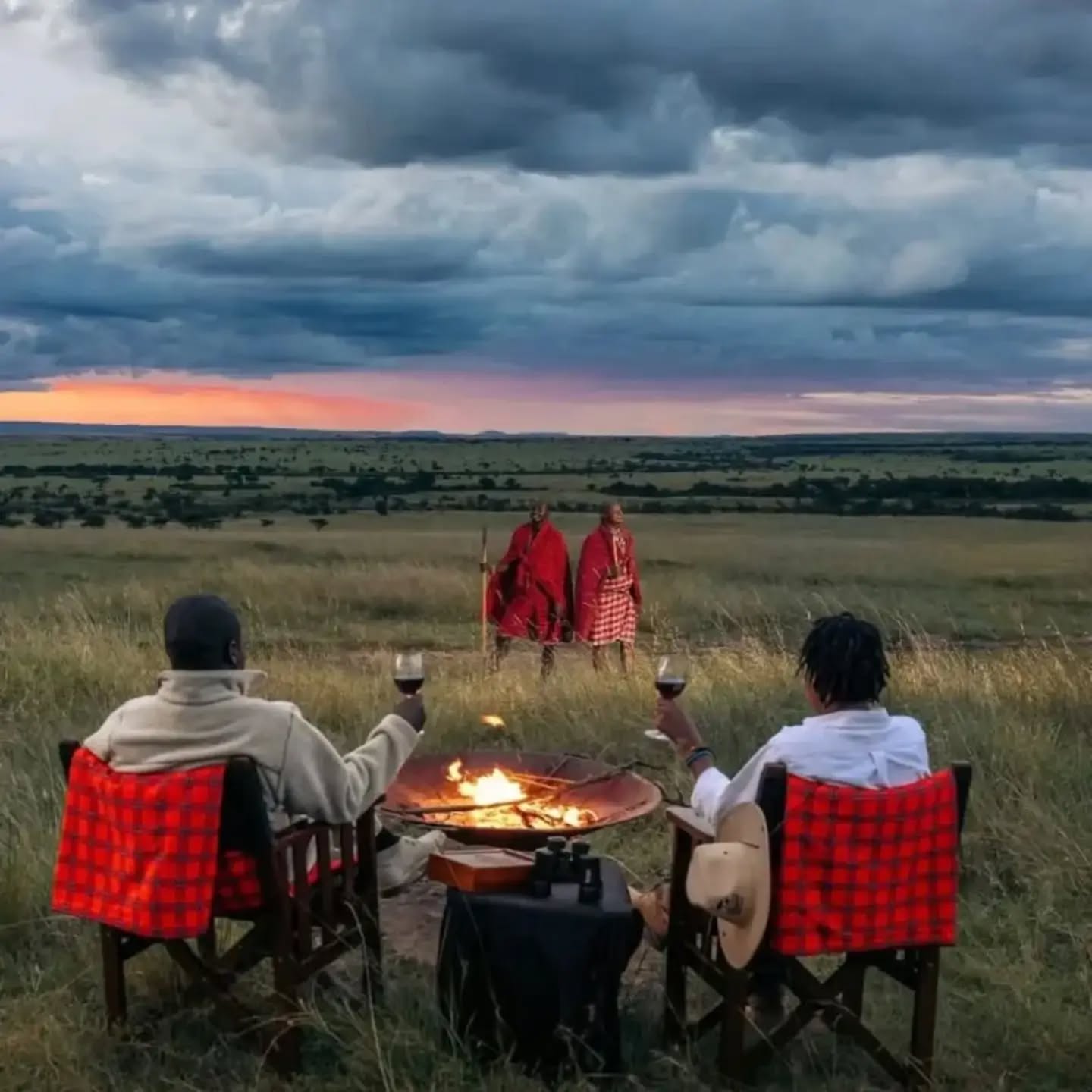 honeymooners toasting to the evening while being guarded by masai warriors